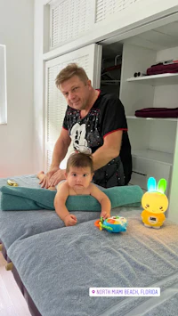 a baby is being massaged by a man in a room